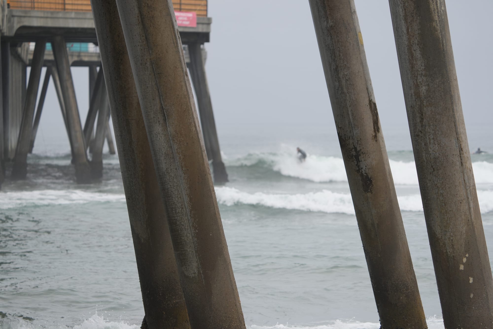 Looking through the pier pilings at a wave