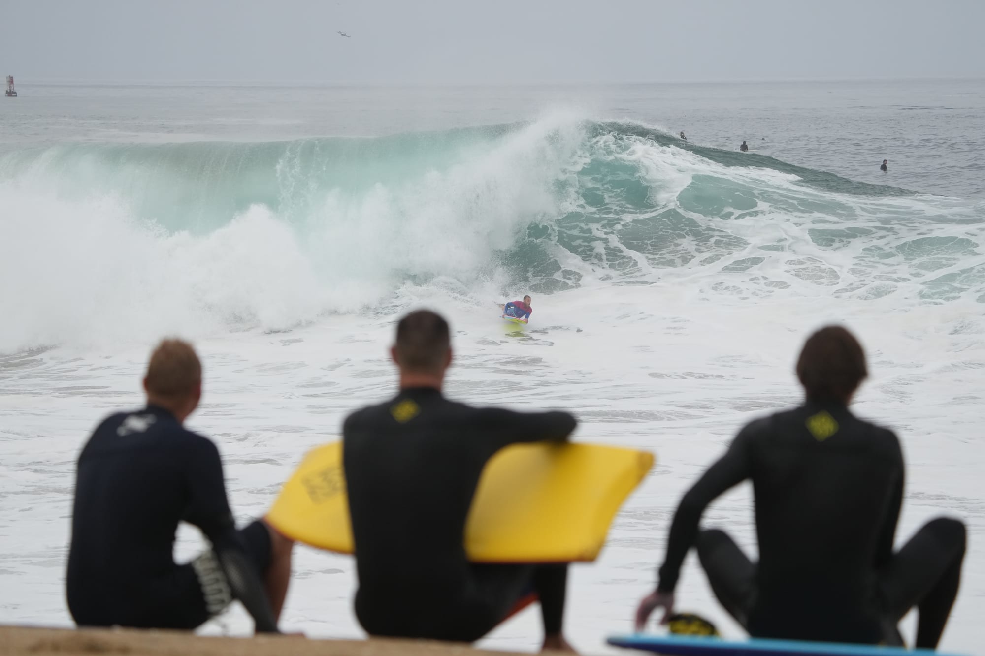 Three surfers on the wall checking the swell