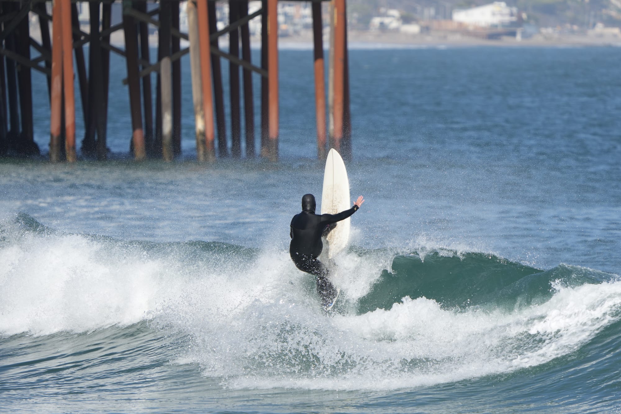 Surfer throwing spray next to the pier