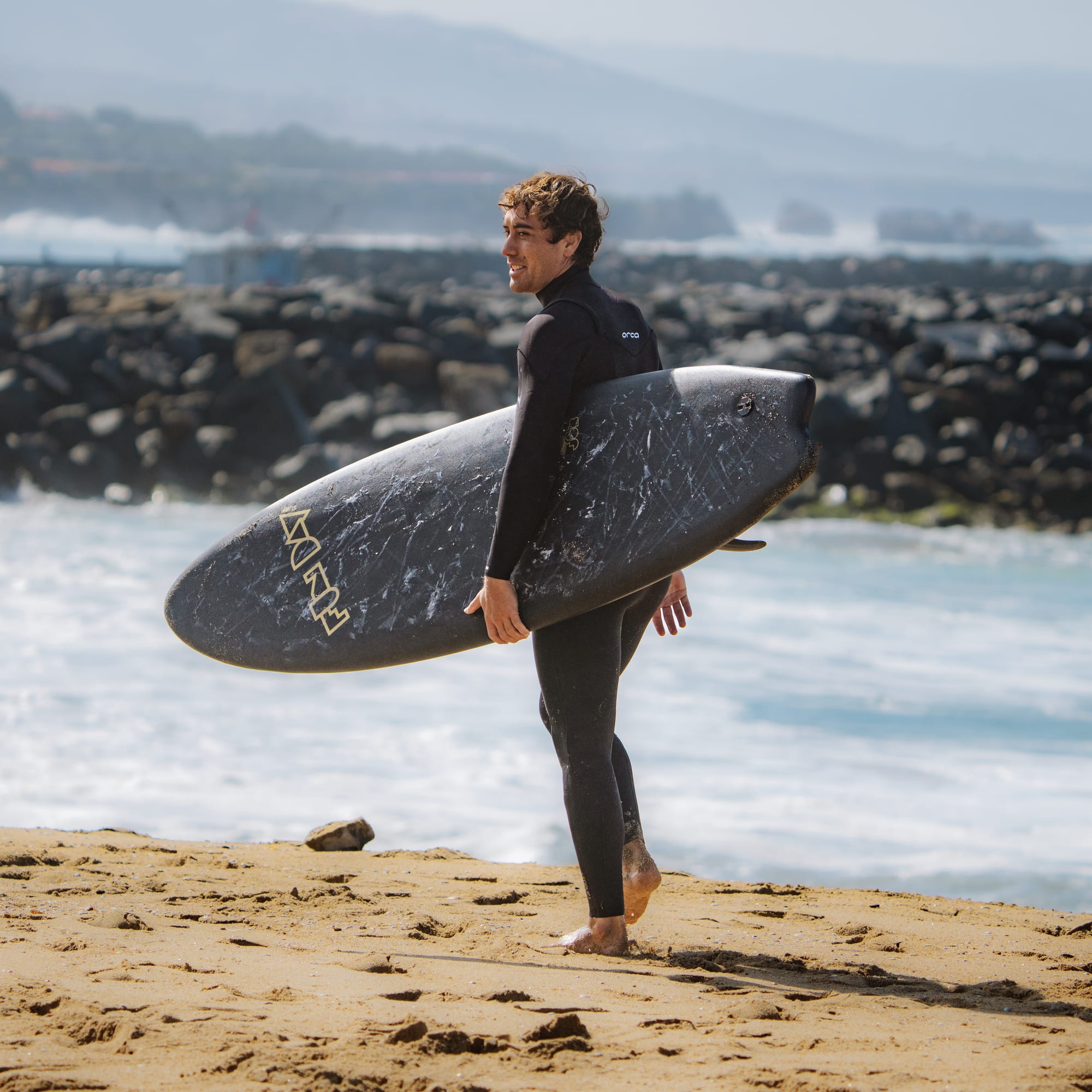 Surfer carrying his board along the jetty