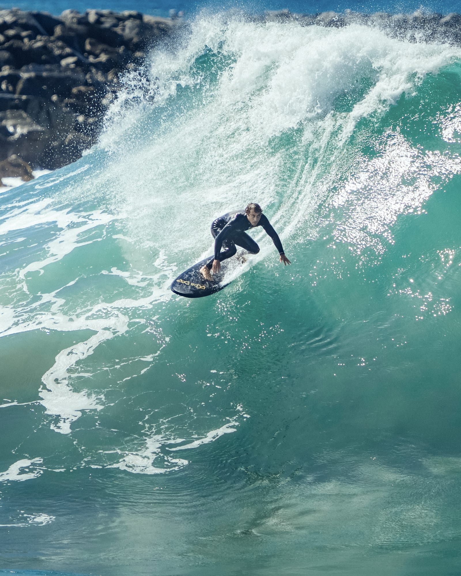 Surfer under the lip of a backlit wave