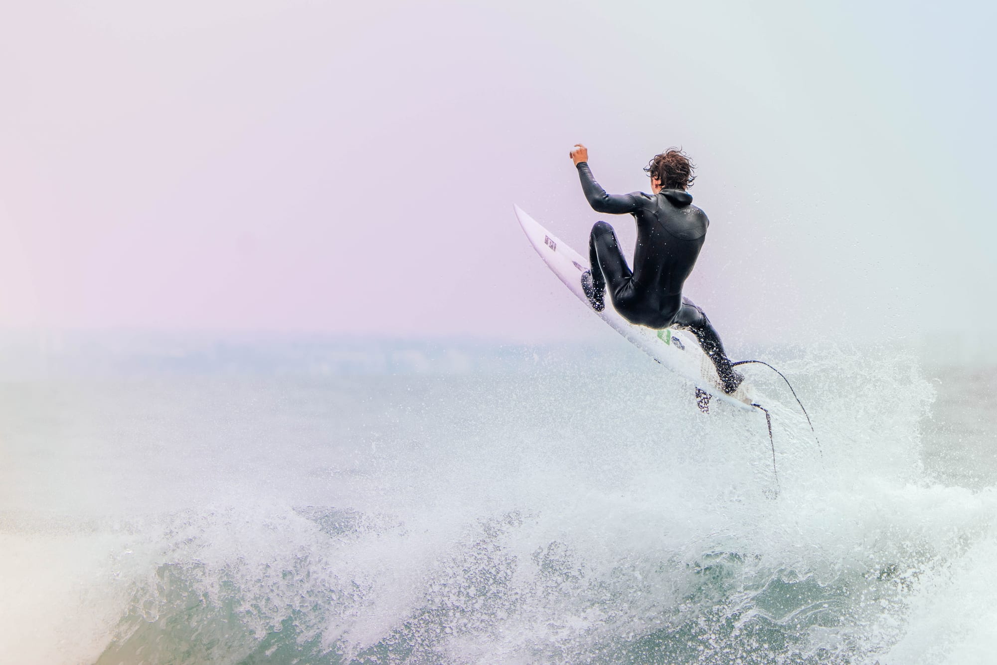 Surfer boosting out of a wave at dusk